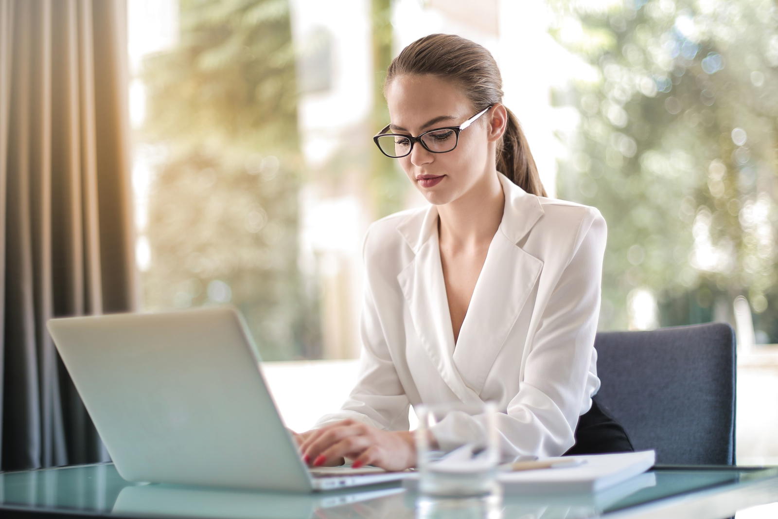 Confident woman typing on laptop in workplace