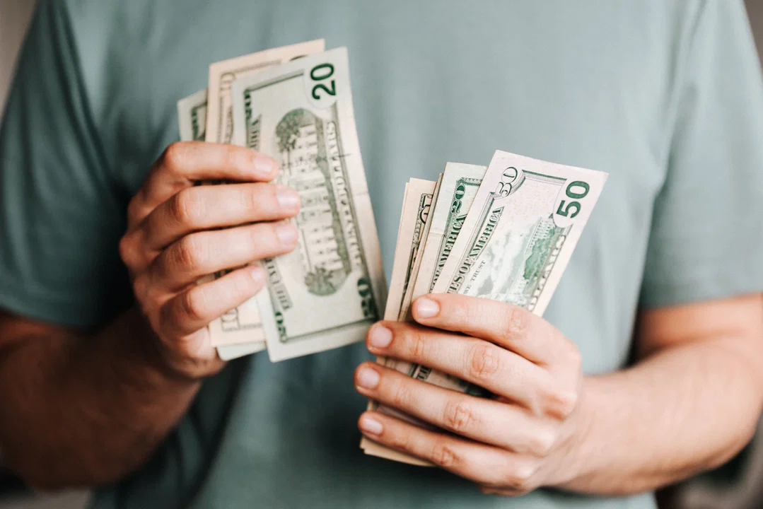 Person holding money — how to save on Duolingo English Test fees with coupon codes