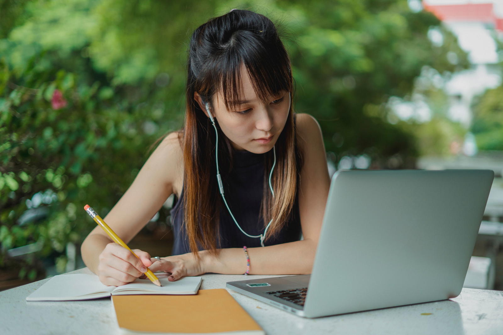 Focused woman with laptop and notebook studying