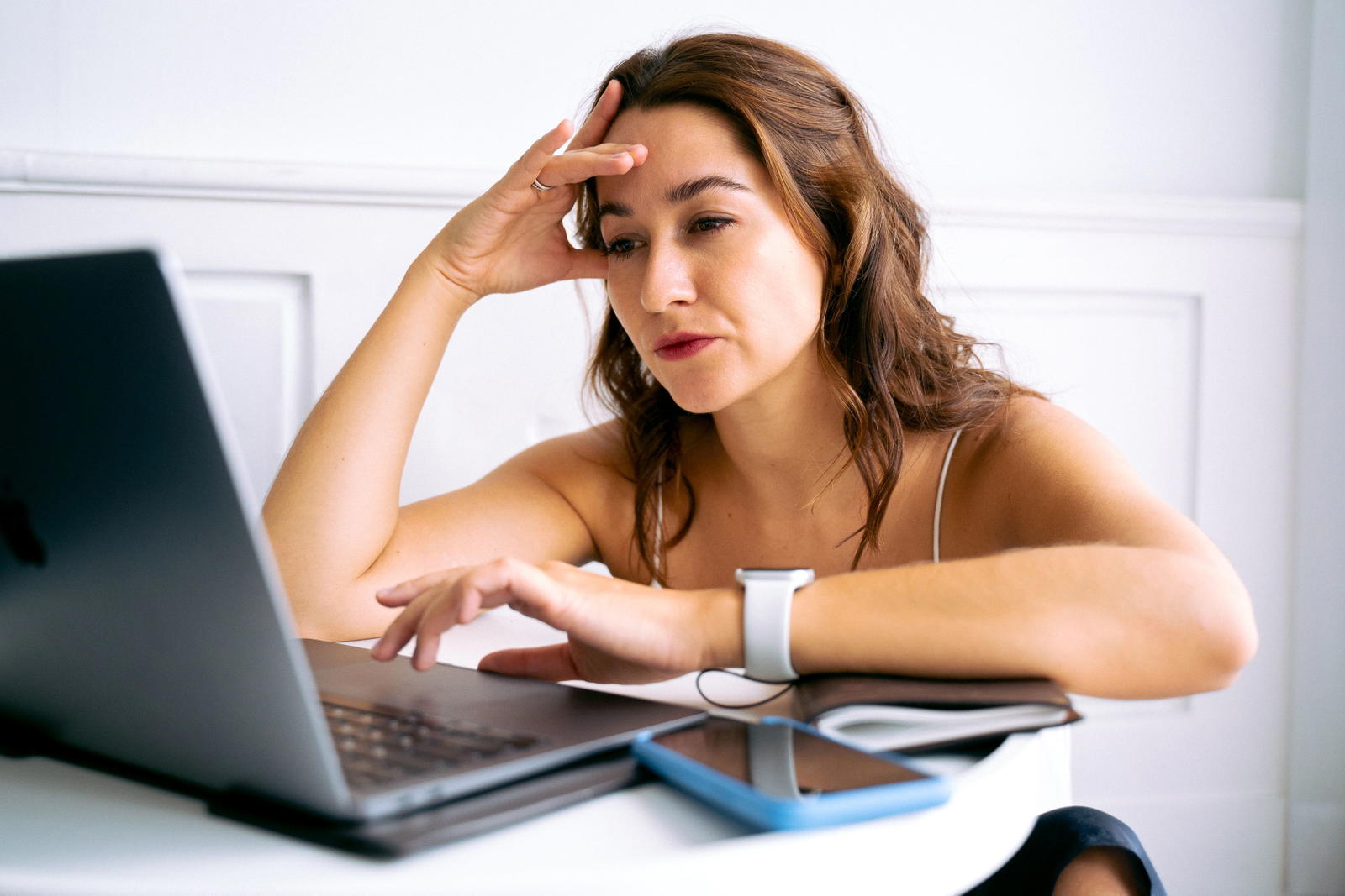 Frustrated woman with hand on head using laptop