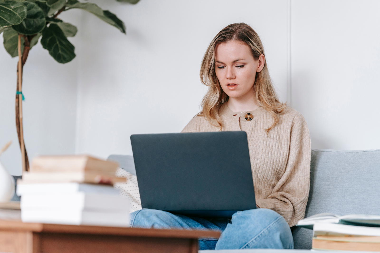 Student studying at home with laptop on sofa — general English study that won't raise DET scores