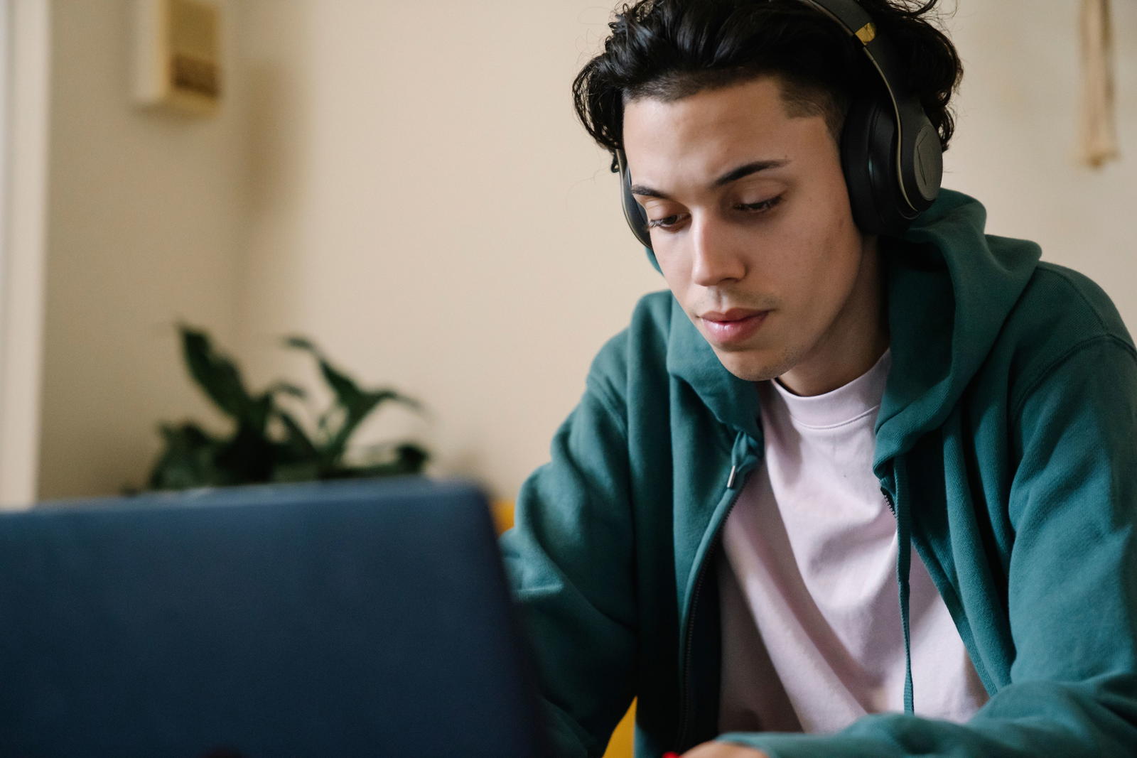 Student with headphones focused on laptop during online English test