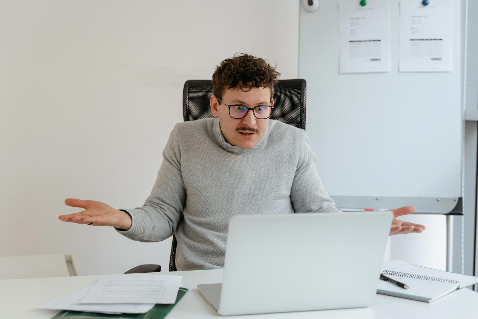 Confused man gesturing at his laptop screen during a video call