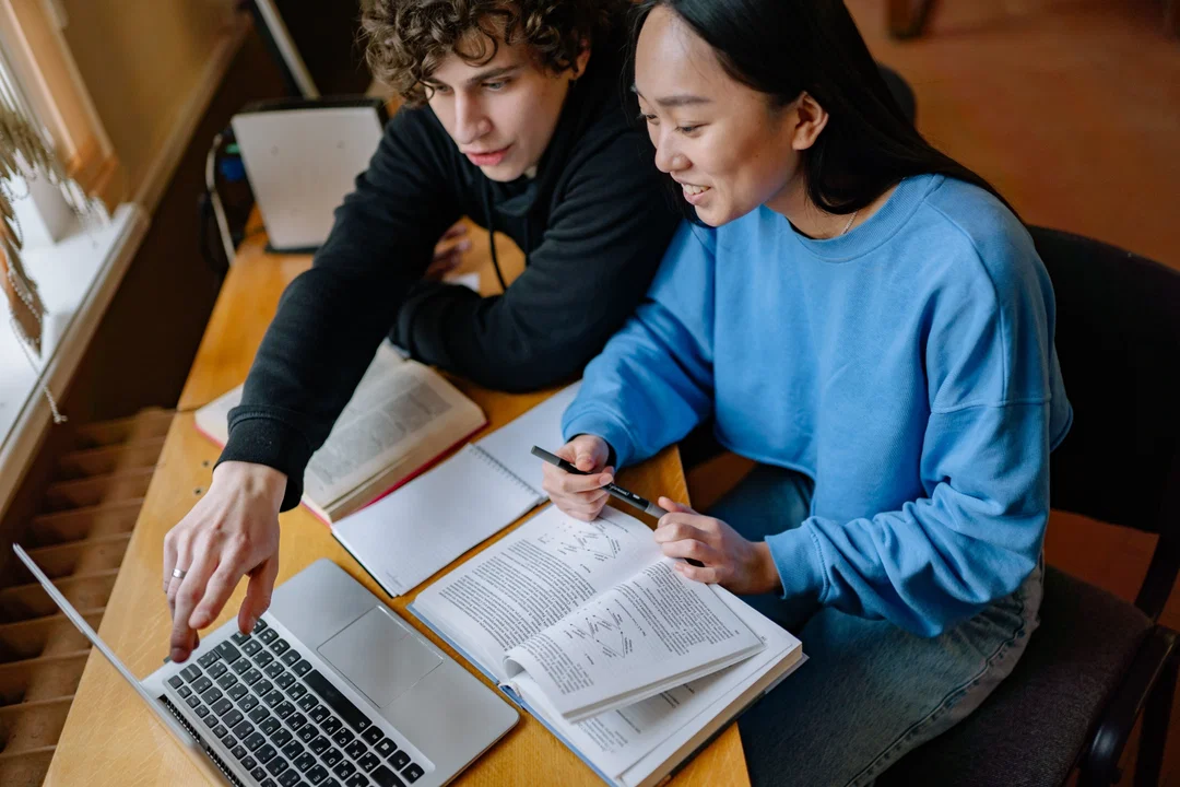 Two students studying together, looking at laptop screen